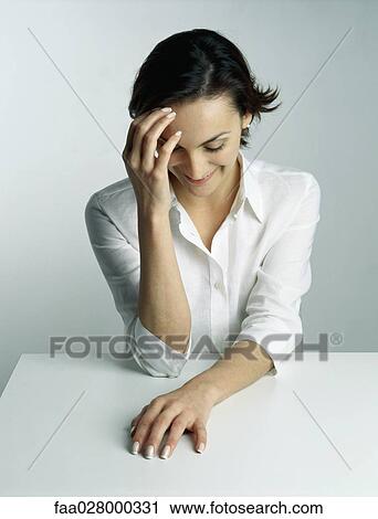 Woman sitting with head down, hand in front of face, portrait View Large Photo Image Stock Image - Woman sitting with head down, hand in front of face, portrait. Fotosearch