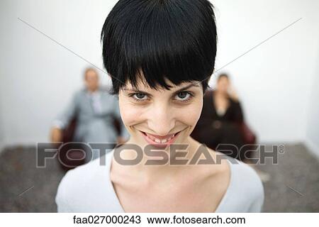 Stock Image - Woman smiling at camera, one eyebrow raised, close-up. Fotosearch
