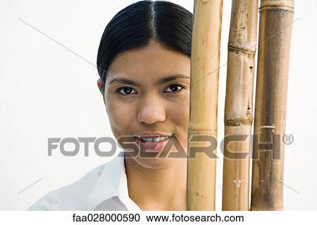 Woman standing behind bamboo stacks, looking at camera, portrait View Large Photo Image Stock Image - Woman standing behind bamboo stacks, looking at camera, portrait. Fotosearch