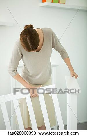 Woman standing in nursery, putting together baby crib View Large Photo Image Stock Photo - Woman standing in nursery, putting together baby crib. Fotosearch