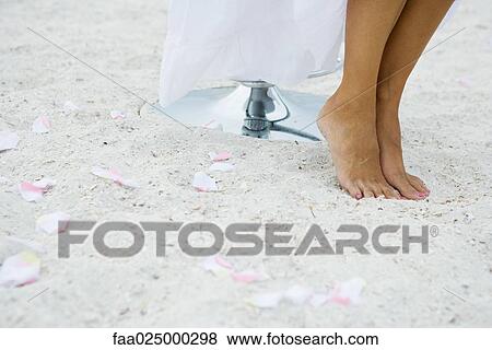 Woman standing on tiptoe in sand among scattered flower petals, cropped view of feet View Large Photo Image Stock Photo - Woman standing on tiptoe in sand among scattered flower petals, cropped view of feet. Fotosearch