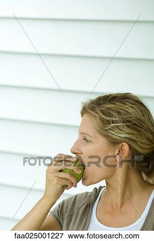 Woman taking bite out of apple, side view View Large Photo Image Stock Photo - Woman taking bite out of apple, side view. Fotosearch