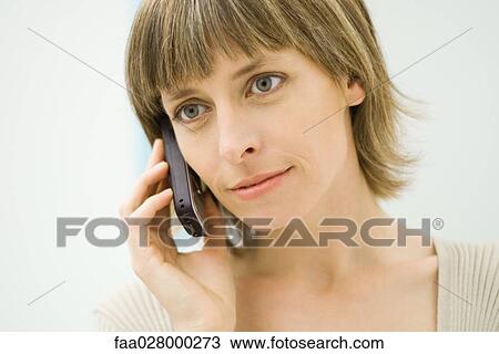 Stock Image - Woman using cell phone, looking away, close-up. Fotosearch