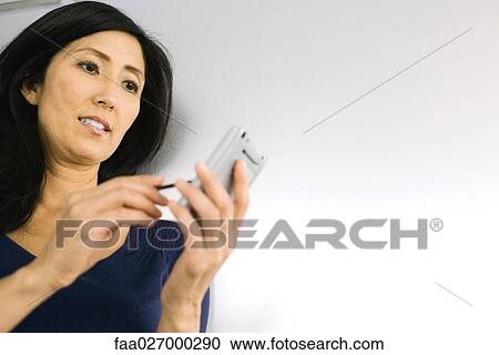Stock Image - Woman using palmtop, low angle view. Fotosearch