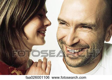 Woman whispering into man's ear, both smiling, close-up View Large Photo Image Stock Photograph - Woman whispering into man's ear, both smiling, close-up. Fotosearch