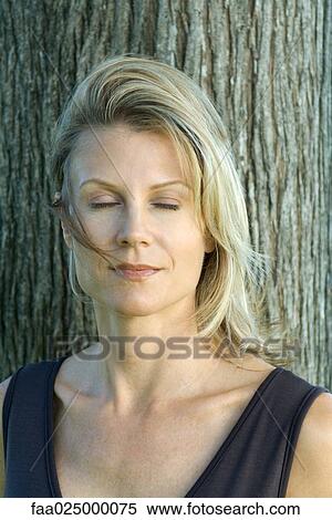 Woman with eyes closed, tree trunk in background View Large Photo Image Stock Photography - Woman with eyes closed, tree trunk in background. Fotosearch