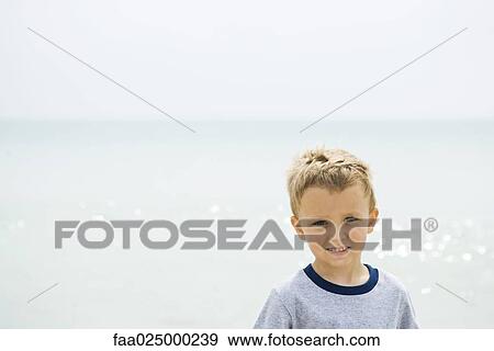 Young boy at the beach, smiling at camera, portrait View Large Photo Image Stock Photo - Young boy at the beach, smiling at camera, portrait. Fotosearch