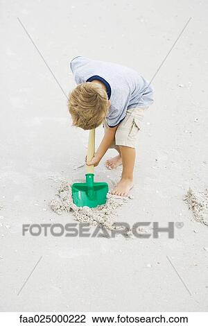 Young boy digging in sand with shovel, full length View Large Photo Image Stock Image - Young boy digging in sand with shovel, full length. Fotosearch