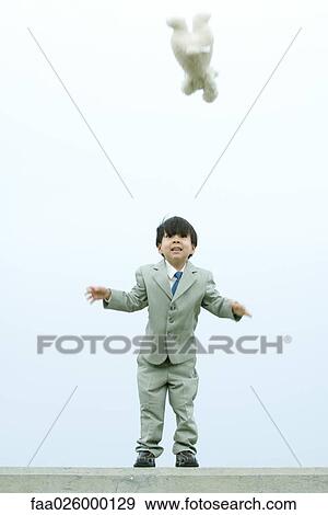 Young boy dressed in suit, throwing teddy bear in the air, looking up View Large Photo Image Stock Photo - Young boy dressed in suit, throwing teddy bear in the air, looking up. Fotosearch