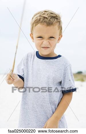 Young boy holding up stick, squinting at camera View Large Photo Image Stock Image - Young boy holding up stick, squinting at camera. Fotosearch