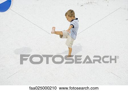 Young boy kicking beach ball at the beach, side view View Large Photo Image Stock Image - Young boy kicking beach ball at the beach, side view. Fotosearch