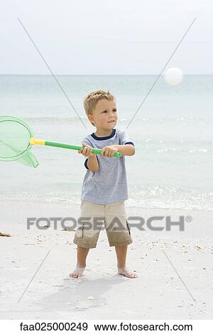 Young boy standing at the beach, holding up net to catch ball View Large Photo Image Stock Photo - Young boy standing at the beach, holding up net to catch ball. Fotosearch