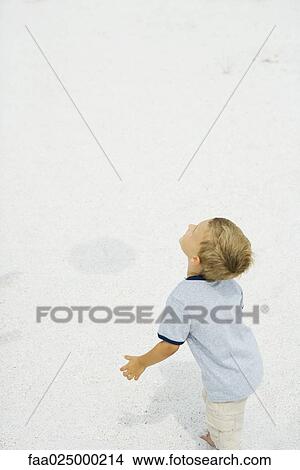 Young boy standing at the beach with head back, looking up View Large Photo Image Picture - Young boy standing at the beach with head back, looking up. Fotosearch