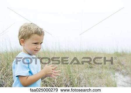 Young boy standing in tall grass, looking away, side view View Large Photo Image Stock Photo - Young boy standing in tall grass, looking away, side view. Fotosearch