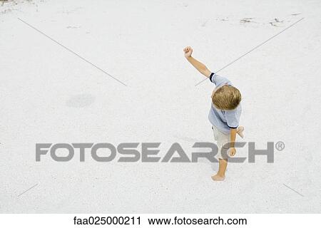 Young boy walking on the beach with one arm raised, high angle view View Large Photo Image Stock Image - Young boy walking on the beach with one arm raised, high angle view. Fotosearch