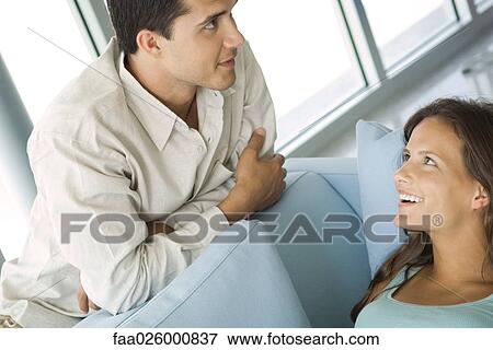 Young couple chatting together, female lying on couch, both smiling View Large Photo Image Stock Photo - Young couple chatting together, female lying on couch, both smiling. Fotosearch