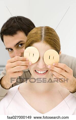 Young couple, man holding slices of fruit over woman's eyes View Large Photo Image Stock Photo - Young couple, man holding slices of fruit over woman's eyes. Fotosearch