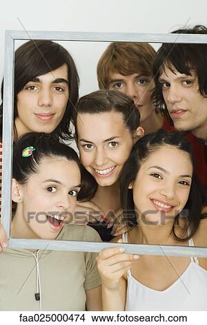 Young friends smiling at camera through picture frame, group portrait View Large Photo Image Picture - Young friends smiling at camera through picture frame, group portrait. Fotosearch
