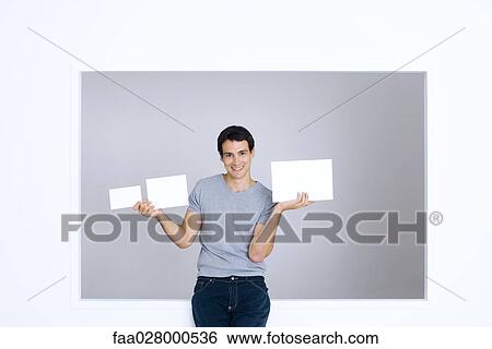 Young man holding up three blank signs of different sizes View Large Photo Image Stock Photograph - Young man holding up three blank signs of different sizes. Fotosearch