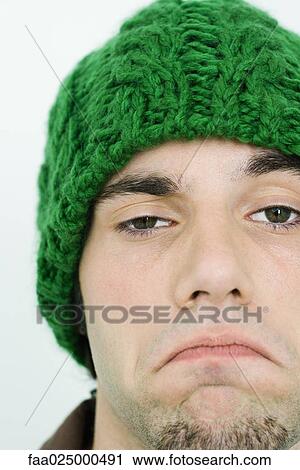 Young man in knit hat frowning at camera, cropped view View Large Photo Image Stock Image - Young man in knit hat frowning at camera, cropped view. Fotosearch