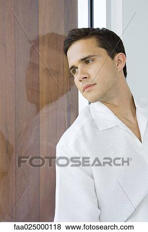 Young man leaning against window, looking out, close-up View Large Photo Image Stock Photo - Young man leaning against window, looking out, close-up. Fotosearch