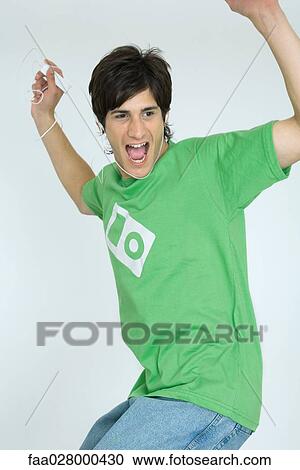Young man listening to MP3 player, dancing, arms raised View Large Photo Image Stock Image - Young man listening to MP3 player, dancing, arms raised. Fotosearch