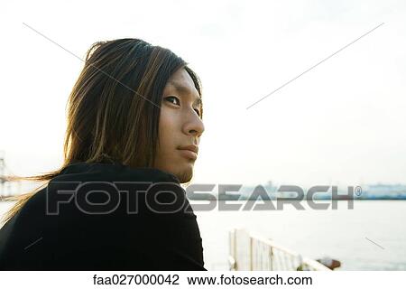 Young man outdoors, looking away, close-up View Large Photo Image Stock Image - Young man outdoors, looking away, close-up. Fotosearch