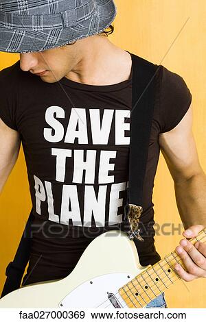 Young man playing electric guitar, wearing tee-shirt reading "save the planet" View Large Photo Image Stock Photo - Young man playing electric guitar, wearing tee-shirt reading "save the planet". Fotosearch