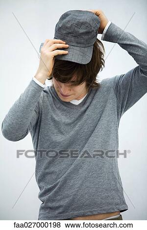 Young man putting on cap, head down, close-up View Large Photo Image Stock Photo - Young man putting on cap, head down, close-up. Fotosearch