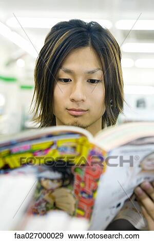 Stock Photo - Young man reading manga-style comic book. Fotosearch
