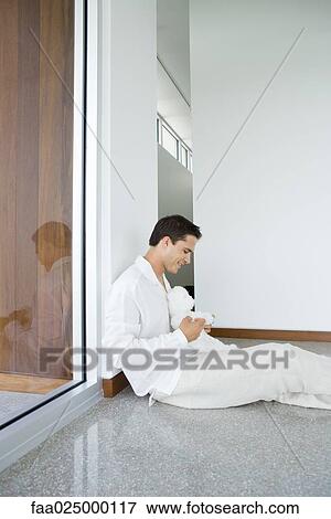 Young man sitting on the ground holding teddy bear View Large Photo Image Stock Photo - Young man sitting on the ground holding teddy bear. Fotosearch