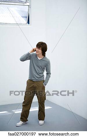 Young man standing with hand in pocket, looking away, high angle view View Large Photo Image Stock Photo - Young man standing with hand in pocket, looking away, high angle view. Fotosearch