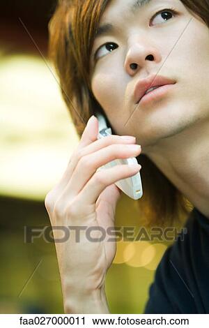 Young man using cell phone, looking up, close-up View Large Photo Image Stock Image - Young man using cell phone, looking up, close-up. Fotosearch