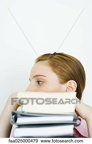Young woman behind stack of books, looking away View Large Photo Image Stock Photo - Young woman behind stack of books, looking away. Fotosearch