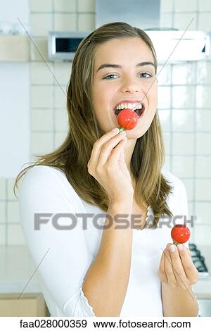 Young woman eating radish in kitchen, portrait View Large Photo Image Stock Photo - Young woman eating radish in kitchen, portrait. Fotosearch