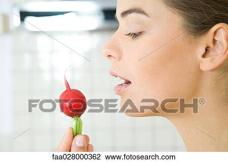 Young woman holding up radish, profile, close-up View Large Photo Image Stock Image - Young woman holding up radish, profile, close-up. Fotosearch