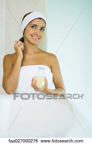 Young woman in towel applying perfume, smiling View Large Photo Image Stock Photograph - Young woman in towel applying perfume, smiling. Fotosearch