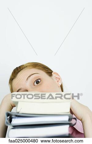 Young woman looking at camera over stack of books, head tilted View Large Photo Image Stock Image - Young woman looking at camera over stack of books, head tilted. Fotosearch