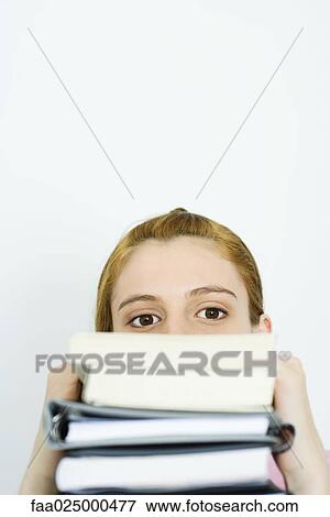 Young woman looking at camera over stack of books View Large Photo Image Stock Photo - Young woman looking at camera over stack of books. Fotosearch