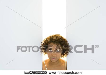 Young woman looking through gap in wall, cropped view View Large Photo Image Stock Image - Young woman looking through gap in wall, cropped view. Fotosearch