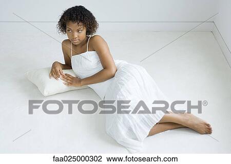 Young woman lying on cushion on the ground, looking away, full length View Large Photo Image Stock Image - Young woman lying on cushion on the ground, looking away, full length. Fotosearch