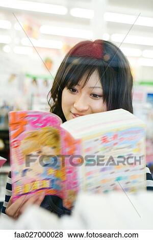 Young woman reading manga-style comic book, smiling View Large Photo Image Stock Photo - Young woman reading manga-style comic book, smiling. Fotosearch