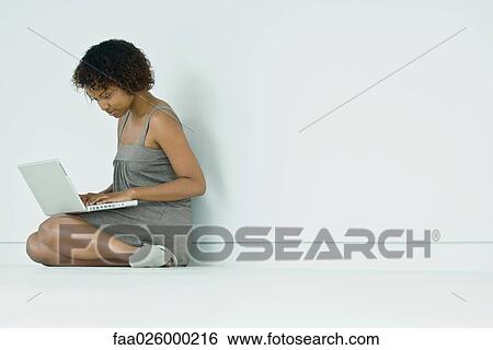 Young woman sitting on the ground, using laptop computer View Large Photo Image Stock Photograph - Young woman sitting on the ground, using laptop computer. Fotosearch