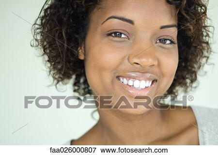 Stock Photo - Young woman smiling at camera, close-up, portrait. Fotosearch