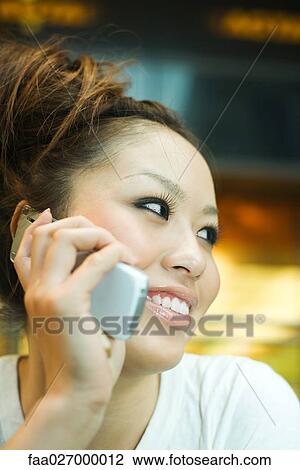 Young woman using cell phone, smiling, looking away, close-up View Large Photo Image Stock Image - Young woman using cell phone, smiling, looking away, close-up. Fotosearch