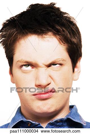 Picture - Teenage boy rolling eyes and raising one corner of mouth, head shot, close-up, white background. Fotosearch