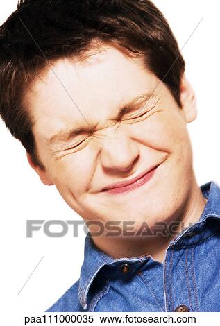 Stock Photography - Teenage boy squinting eyes shut, close-up, portrait. Fotosearch