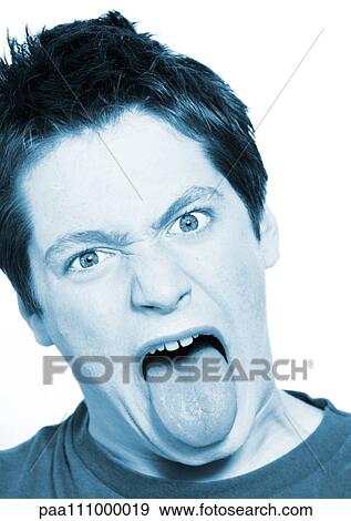 Stock Photo - Teenage boy sticking out tongue, close-up, portrait. Fotosearch