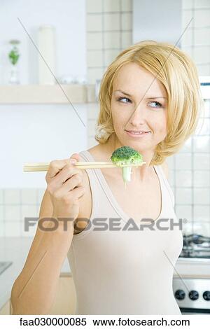 Blonde woman holding piece of broccoli with chopsticks View Large Photo Image Stock Photography - Blonde woman holding piece of broccoli with chopsticks. Fotosearch