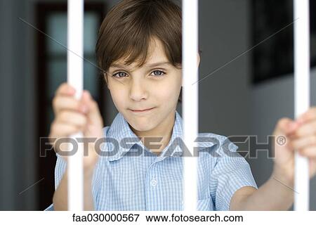 Stock Photo - Boy behind bars, smiling at camera. Fotosearch